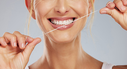 Image showing Teeth flossing, dental wellness and woman with smile while cleaning mouth against grey mockup studio background. Hands of model with string to care for tooth health and oral healthcare with smile
