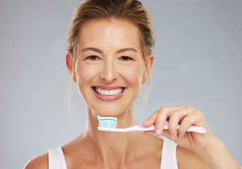 Image showing Senior woman and portrait with toothbrush for dental treatment and teeth whitening at grey studio. Mature, healthy and happy lady with toothpaste for mouth cleaning and white smile face mockup.