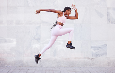 Image showing Energy, sports and black woman jump running outdoor for fitness, wellness and outdoor training with wall mockup. Young, healthy african girl in athlete runner clothes for fashion mock up background