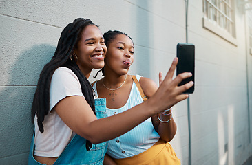 Image showing Black women, friends and phone selfie in city, street or outdoor. Relax, bonding and African girls spending quality time together, comic face and sharing picture post on social media with 5g mobile.