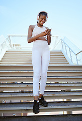 Image showing Smile, fitness and black woman on a phone for music, social media content and streaming podcast via headphones. Happy, city and young girl checking progress on a wellness or exercise app in Africa