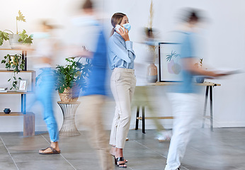 Image showing Covid, office and woman on phone call standing with face mask around work colleagues in motion blur. Female employee on mobile smartphone calling in a busy workplace of fast business people walking