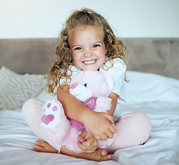 Image showing Children, teddy bear and girl child hug her stuffed animal with a smile in her house. Portrait of kid, happy and safe with an adorable or cute female holding a fluffy toy sitting on a bed