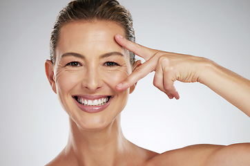 Image showing Skincare, beauty and face of mature woman with anti aging product to reduce lines and wrinkles against grey mockup studio background. Portrait of happy model showing care for skin with cosmetology