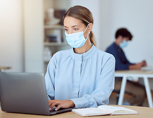 Image showing Laptop, face mask and corporate employee working on a project while sitting at a desk in the office. Professional woman typing company documents on her computer during a global covid pandemic.