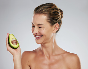 Image showing Mature woman, happy and avocado in hand for skin health, wellness and face in portrait. Mature model, dermatology and smile with fruit for skincare, anti aging and beauty with natural facial product