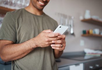 Image showing Hands, phone and man texting in a kitchen, relax and smile while reading social media message. Internet, communication and guy planning fun vacation day, streaming and enjoying online app in his home