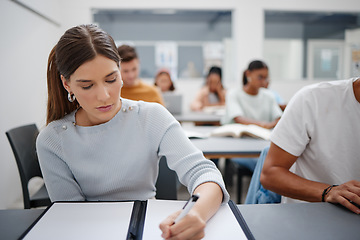 Image showing Woman, student and writing university exam in classroom for higher education, scholarship and training. Focused female learning and taking notes in workshop with group of college students