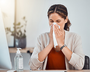 Image showing Covid, sick and woman blowing her nose with a tissue while working in her modern office during pandemic. Flu, cold or sinus allergy sneeze of girl from mexico sitting at her desk with health problems