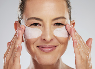 Image showing Eye wellness, skincare and mature woman with dermatology product for face against a grey studio background. Portrait of an elderly spa model with patch cosmetics for eyes for clean facial skin