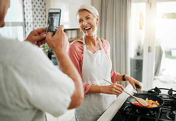 Image showing Phone, man and woman taking a picture and cooking healthy food for dinner in a kitchen in a happy home. Smile, social media and elderly couple love having fun, memories and enjoying quality time