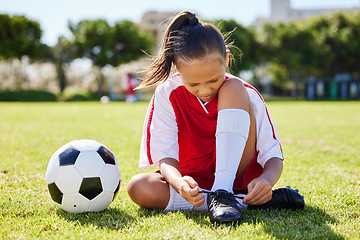 Image showing Sports, soccer and tie shoes with girl on grass for fitness, games and training in brazil event. Motivation, workout and exercise with young child on football field for youth, health and wellness