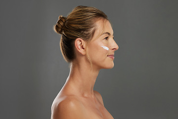 Image showing Beauty, face and skin with a woman using antiaging cream in studio on a gray background with mockup. Skincare, treatment and body care with a beautiful female advertising healthcare from the side