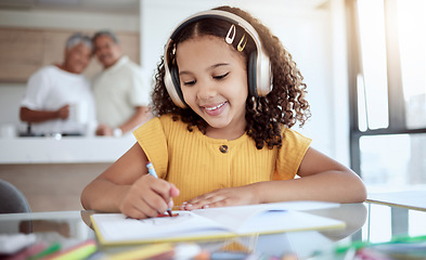 Image showing Girl, homework and music while drawing in book for school, assignment or fun in family home. Child, education and notebook for learning with headphones for audio, radio or streaming in house at desk