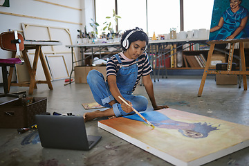 Image showing Laptop, woman artist and painting on floor in studio, gallery or workshop with headphones and streaming music for inspiration. Creative, girl or lady in workspace listen to podcast or focus on canvas