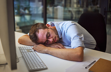 Image showing Burnout, tired and sleep with a business man sleeping on his desk while working on a computer at a desk in his office. Mental health, problem and exhausted with a young male employee at work at night