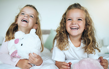 Image showing Children, teddy bear and happy sisters playing together in their bedroom at their family home. Happiness, smile and bond between twin siblings holding a toy while relaxing on a bed in their room.