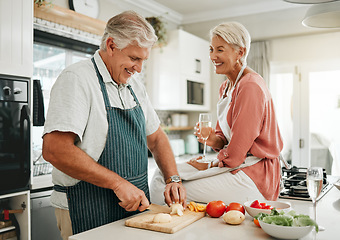 Image showing A happy senior couple, cooking healthy food in kitchen and drinking champaign as they enjoy retirement. Elderly woman with sitting on counter, man with silver laughing and they smile in love together