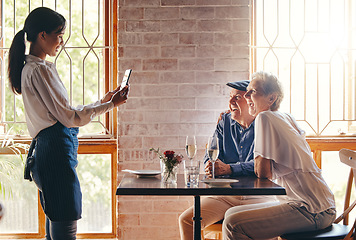 Image showing Photograph, restaurant and date with a senior couple in celebration of an anniversary and waitress using a phone. Service, romance and travel with a man and woman tourist posing for a picture