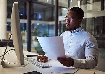 Image showing Contract, documents and data with a businessman working at night on a computer in an office. Research, reading and information with a black male employee at work at a desk on an international company