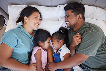 Image showing Happy family, relax on bed in home from above and bonding together in bedroom. Sleep, comfort and rest of caring Indian mom, dad and children or girls smile lying on cozy sheets and playing in house.