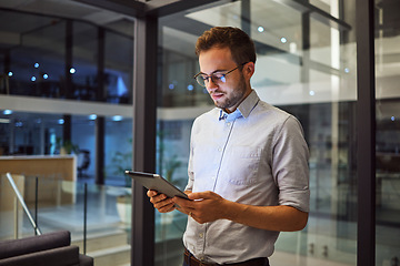 Image showing Businessman working on tablet at night for digital marketing online report at the office. Manager or employee reading communication on internet about tech proposal while working late at a startup job