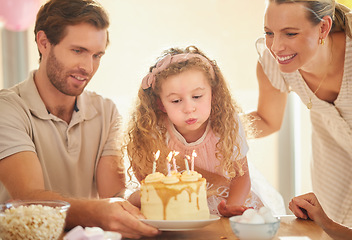 Image showing Birthday, candles and family celebration with cake, parents and girl for a happy family event. Happiness, love and smile of a mother, father and young daughter together blowing a candle in a home