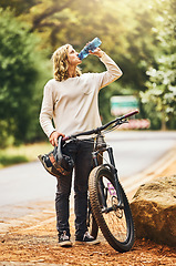 Image showing Health, cycling and woman drinking water on a break in nature to hydrate, wellness and resting outdoors. Sports, exercise and thirsty biker riding bicycle by the road refreshing with liquid