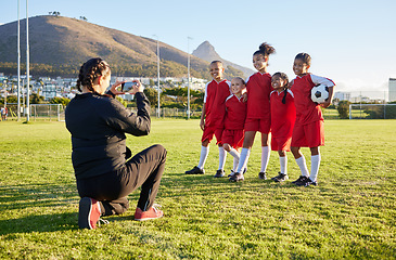 Image showing Soccer, phone and team picture with coach, ball and sports girl group with a smile together on a field. Young female football squad happy with post for social media on a sports ground after training