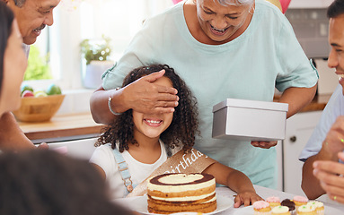 Image showing Child, birthday present and celebration party with grandma covering eyes for gift box surprise from family at home. Cute kid at a table in Puerto Rico house celebrating with cake and snacks on table