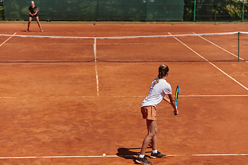 Image showing Young girls in a lively tennis match on a sunny day, demonstrating their skills and enthusiasm on a modern tennis court.