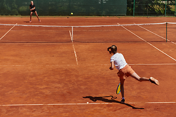 Image showing Young girls in a lively tennis match on a sunny day, demonstrating their skills and enthusiasm on a modern tennis court.