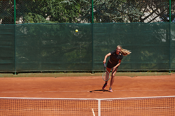 Image showing A young girl showing professional tennis skills in a competitive match on a sunny day, surrounded by the modern aesthetics of a tennis court.