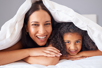 Image showing Children, family and bedroom with a girl and mother in bed under a blanket together for love or care in the home. Kids, trust and happy with a woman her daughter in the house to relax in the morning