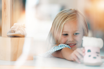 Image showing Happy, fashion and child shopping for shoes at a kids clothing store or boutique in the city. Happiness, smile and young girl customer or shopper choosing boots in a children shop.