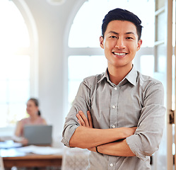 Image showing Asian man, leader and in office stand happy, proud and confident at workplace and with cross arms. Portrait, businessman and entrepreneur focus, positive and smile for successful project in workspace