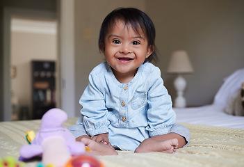 Image showing Happy baby with down syndrome, portrait on bed with smile of Mexican kid with special needs relaxed in home. Happy toddler girl in Mexico with disability and cheerful joy sitting in bedroom.