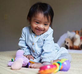 Image showing Happy, smile and baby with down syndrome playing with toys for child development in a bedroom. Happiness, learning and girl child with disability or special needs having play time on a bed at home.