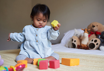 Image showing Down syndrome, daycare and baby on the bed with toys, playing with color shapes and blocks. Child development, special needs and cute girl in bedroom learning, having fun and therapy games for kids