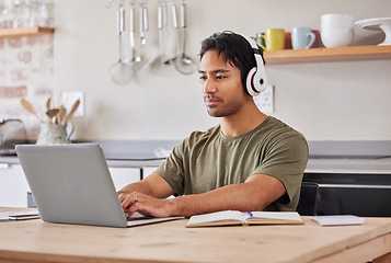 Image showing Laptop, kitchen and student with music headphones to listen to rock song while working on research project. Young gen z man relax at home while streaming audio podcast or radio for peace and wellness