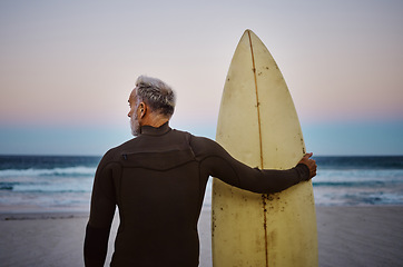 Image showing Beach, man and surfboard with back view for morning cardio fitness and tranquil swim in nature. Senior surfer waiting for low tide at ocean for calm surf waves with peaceful sky at dawn.