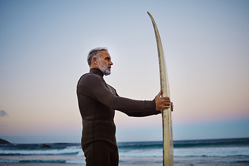 Image showing Surfer, surfboard and senior man at the beach during sunset after surfing on the waves in the sea water. Elderly male on a surf travel vacation in hawaii to enjoy sport, hobby and tropical weather