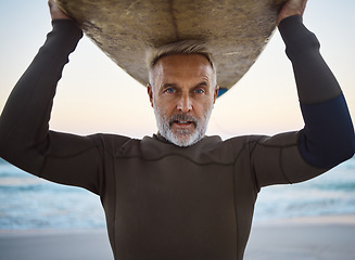 Image showing Beach, surf board on head and a mature surfer man with ocean waves and sea sand. Freedom, water sports and fun on retirement holiday in Australia. Health, fitness and senior in wetsuit for surfing