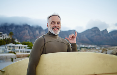 Image showing Senior surfer, surfing at beach for fitness and exercise in retirement on an island travel holiday. Man swimming in Indian ocean on summer vacation, board to surf waves on the sea and shaka hand sign