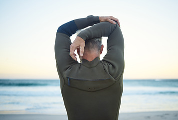 Image showing Fitness, surf and man stretching on beach to warm up before training in ocean water. Fitness, freedom and surfer with wellness, health and active lifestyle doing arm exercise for surfing at seaside.