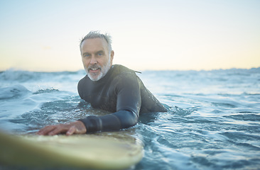 Image showing Senior man, surfing in the ocean of Indonesia and free to travel the world in retirement life. Retired surfer, swimming in the sea for fitness and exercise looking to catch a perfect wave on holiday