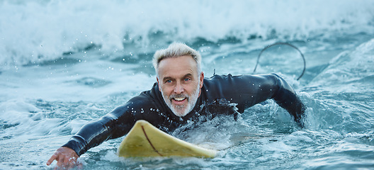 Image showing Surf, sea and sports with a mature man surfer in the water for sport, fitness and surfing during summer. Training, workout and exercise with a male athlete on his surfboard in the ocean alone