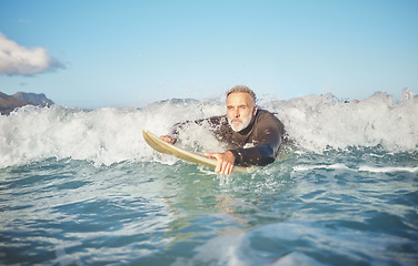 Image showing Ocean waves, senior man surfing on beach and healthy fitness lifestyle in Australia summer holiday. Elderly surfer swimming with surfboard, sea water exercise and relax in retirement travel vacation