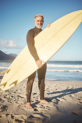 Image showing Surf, sand and sea with a man on the beach for surfing, fitness or exercise while on summer vacation. Sports, workout and training with a mature male surfer outdoor for sport with a surfboard