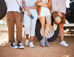 Image showing Road trip, travel and shoes with a friends outdoor by a car during summer for a holiday or vacation. Nature, fashion and stop with men and woman standing by transport while sightseeing outside